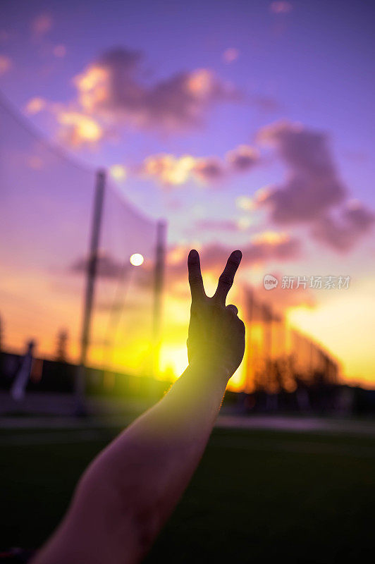 在美丽的夕阳下，手指的剪影做了一个和平的手势
