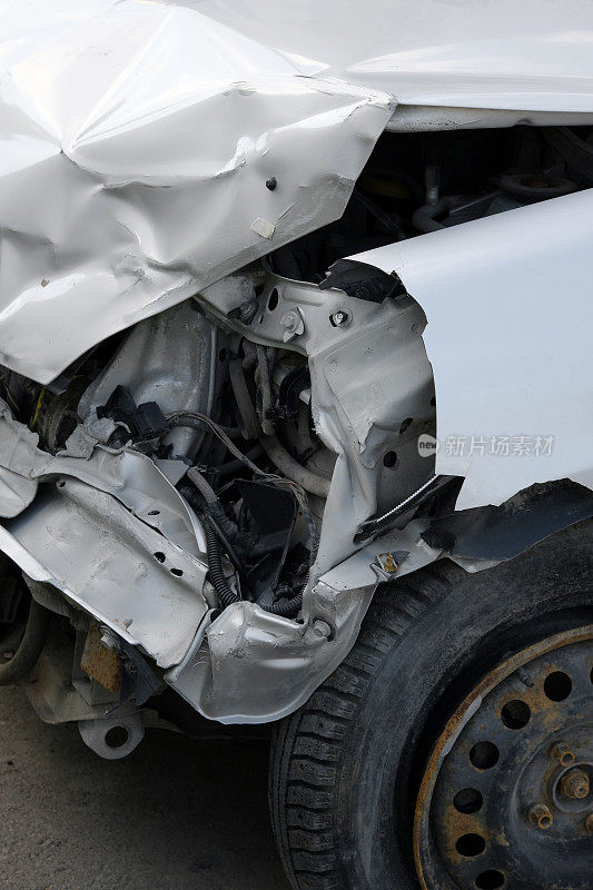 车祸或事故。受损汽车的正面。一辆白色汽车的前部严重受损。破碎的车辆细节或近距离。