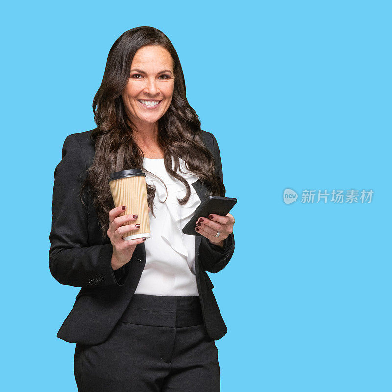 白人女性经理站着，穿着商务装，拿着咖啡杯，用着智能手机