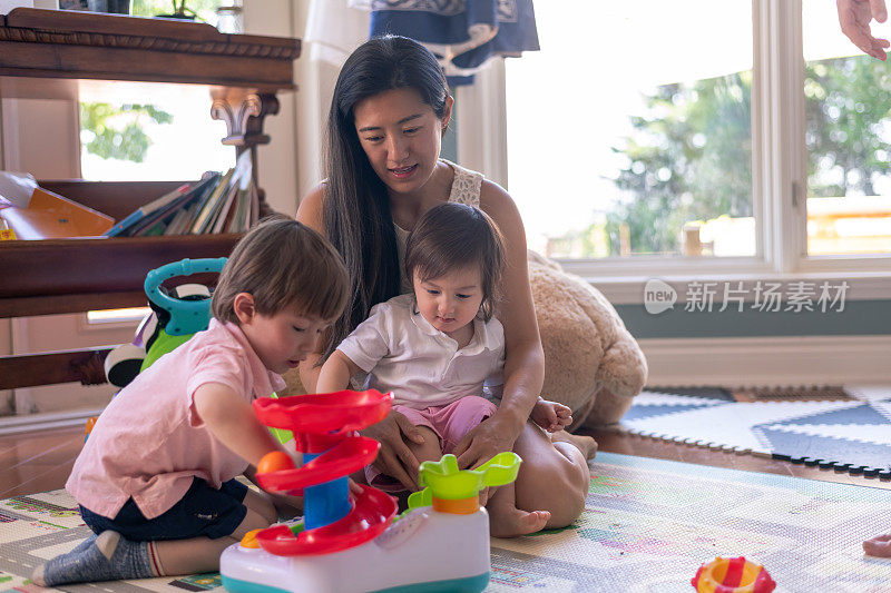 母亲和年幼的儿子们一起在地板上玩玩具