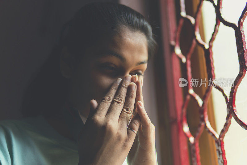 这个悲伤的女孩正在保护自己，戴着口罩，在家里自我隔离。