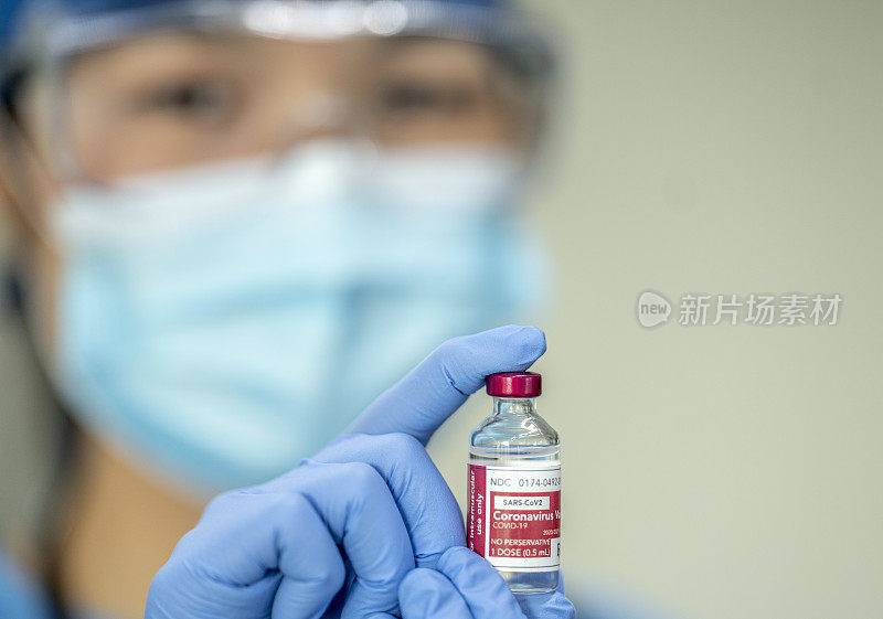 手持新型冠状病毒疫苗瓶的女医务人员