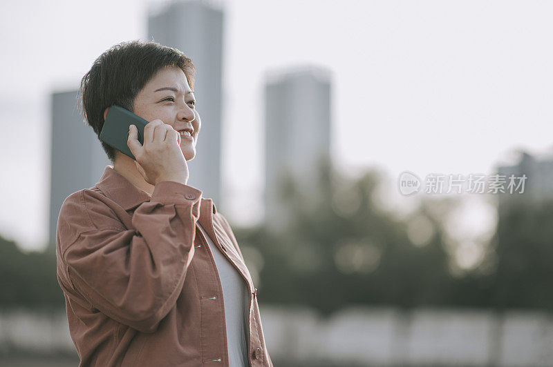 亚洲华人中年妇女在晚上在户外通过电话交谈微笑