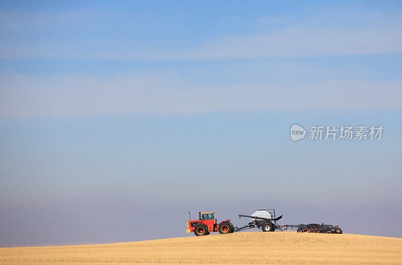 草原农田上的红色拖拉机和播种机