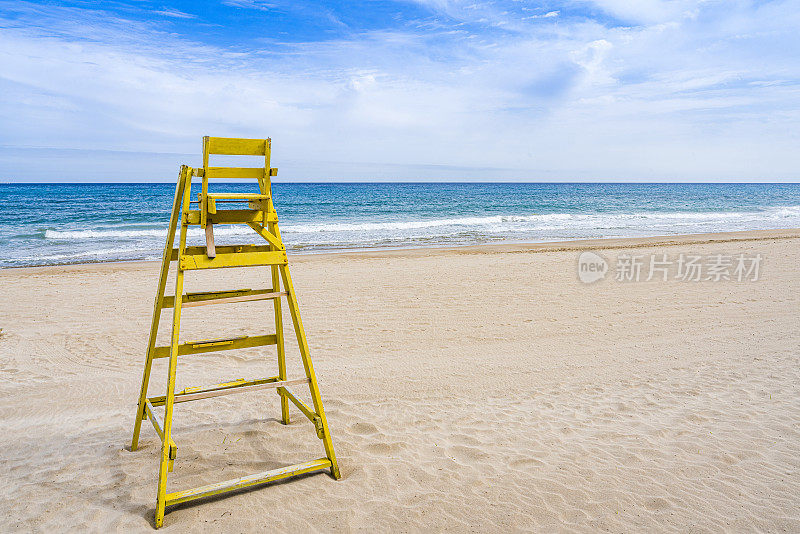 空荡荡的海滩上的黄色救生员椅。本空间