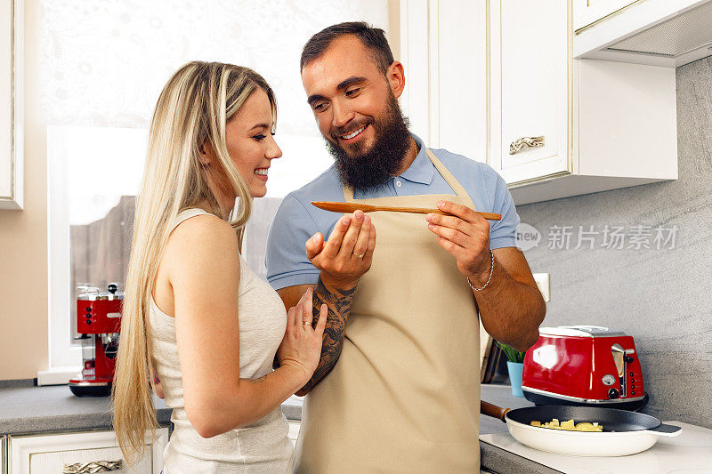 年轻的男人和女人一起在厨房做饭，幸福的夫妇准备食物