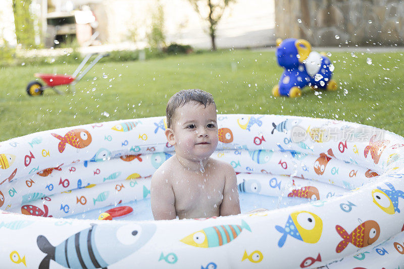 一个小男孩在家里后院的游泳池里玩