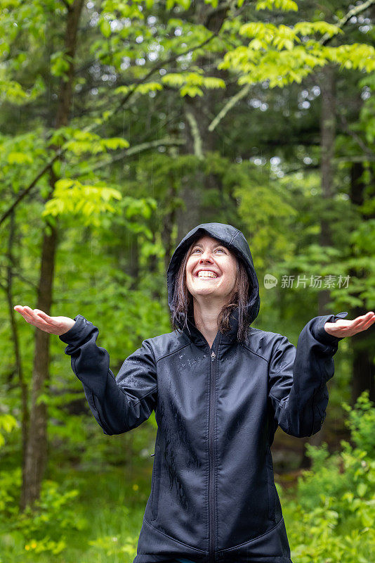 穿着雨衣在森林里徒步旅行的快乐女人