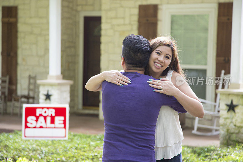 房地产待售。夫妇二人拥抱着，因为他们已经决定买房子了。