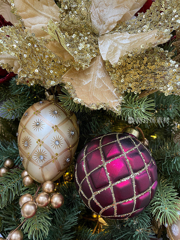 形象的黄金，费伯奇蛋设计，和紫色和金色的闪光绗缝风格的饰品挂在人造圣诞树的树枝，金色的葡萄，绿色云杉针，模糊的白色精灵灯的背景