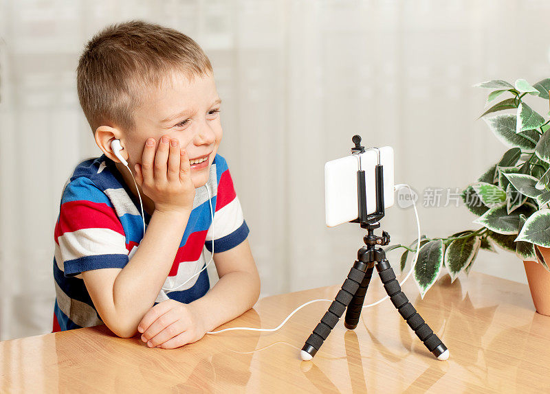 一个戴着耳机的男孩专心地看着手机。孩子们对电子产品的上瘾。学龄前儿童的在线学习