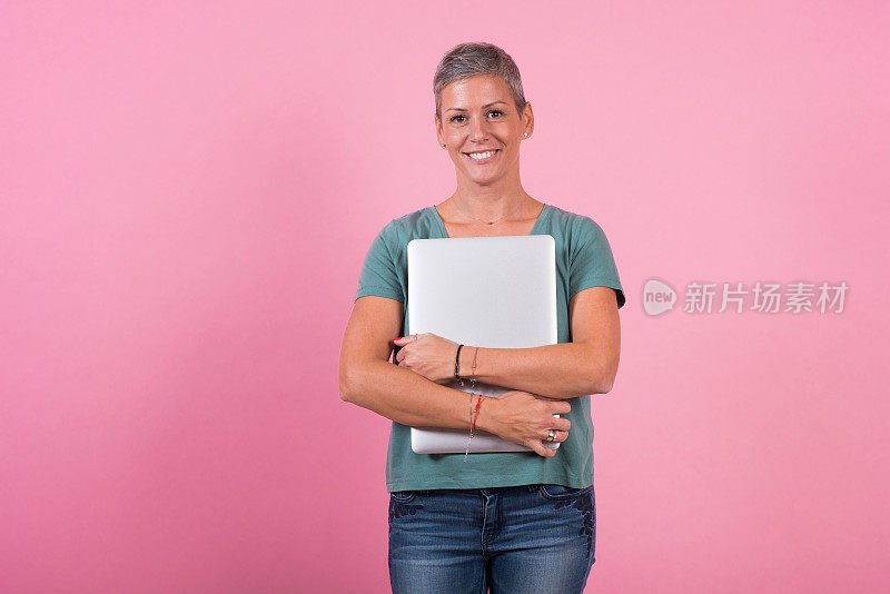 一个快乐的女人拿着笔记本电脑的工作室肖像