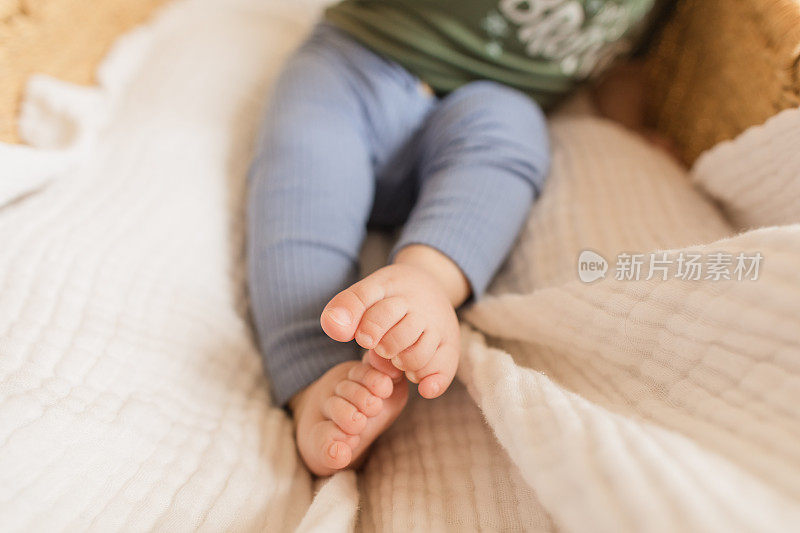 7个月大的男婴，12个脚趾(多指畸形)躺在一个舒适的海草摩西篮子里，白色亚麻布