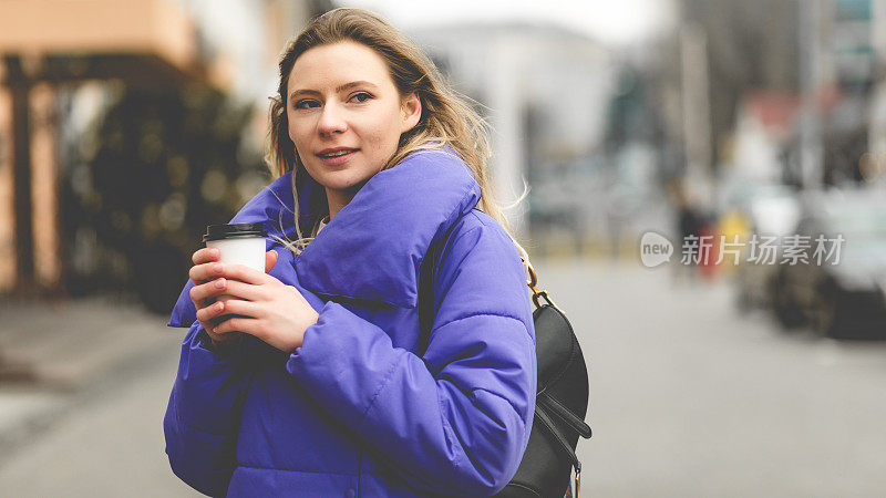 美女肖像时尚女子穿紫色夹克在街上。概念照片与一杯温暖的饮料