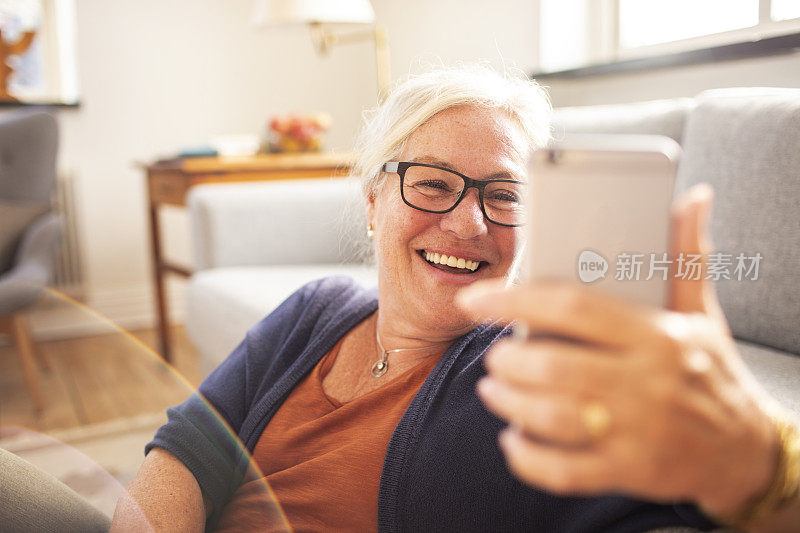 一位老年妇女在一所房子的客厅里用手机