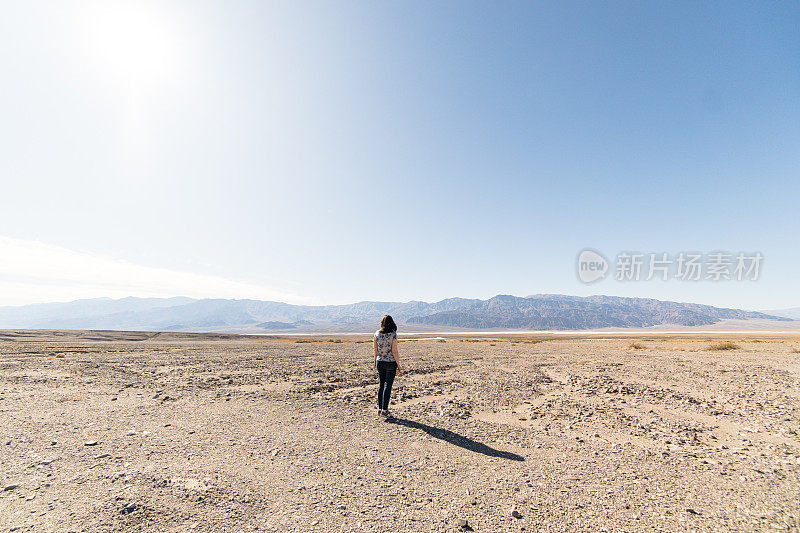 一个女人在死亡谷独自徘徊在晴朗的天空下，烈日炎炎