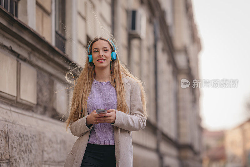 年轻自信的女人在街上听音乐的肖像