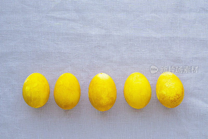 自然染色的黄色鸡蛋在中性背景，俯视图，平lay。复活节快乐。文本复制空间。