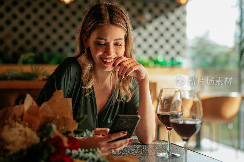 快乐的女人在餐厅使用手机。