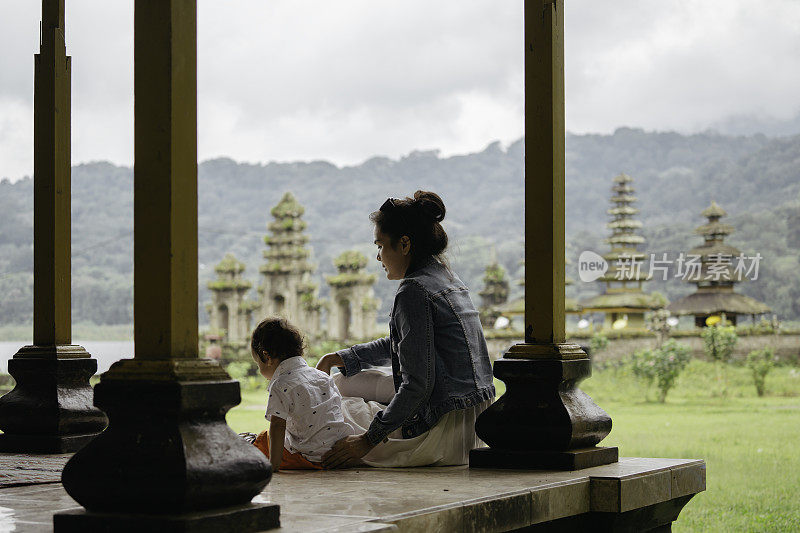 亚洲，印度尼西亚，巴厘岛，亚洲家庭坐在亭子内享受旅行，在坦布林安水庙前，一边观光。