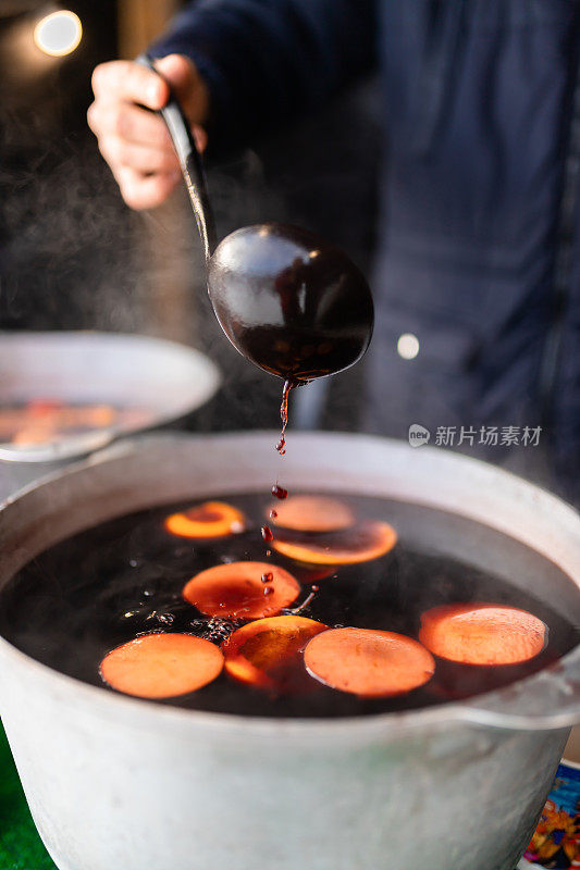 集市上用肉桂和柑橘在大锅里酿造的圣诞热葡萄酒。烹饪传统的圣诞和新年饮料