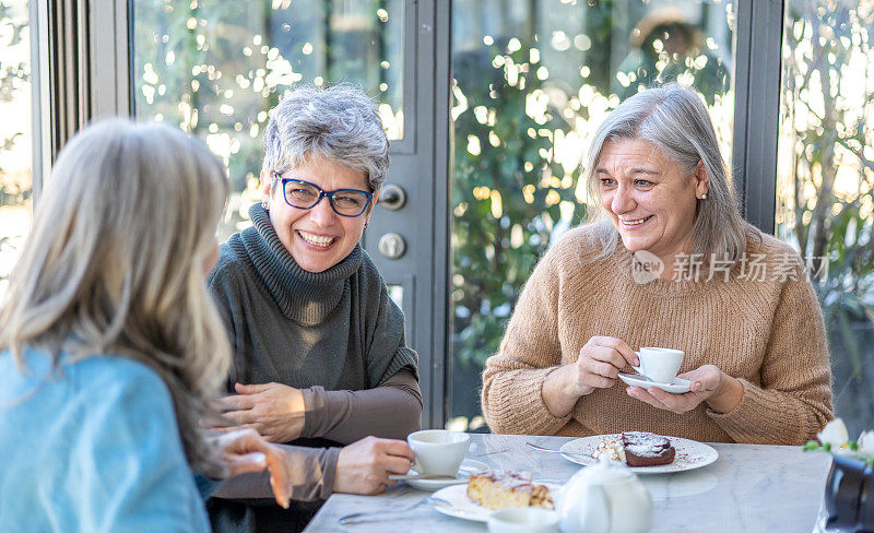 一群微笑的成熟女人一起吃早餐。三位资深女性朋友一起大笑