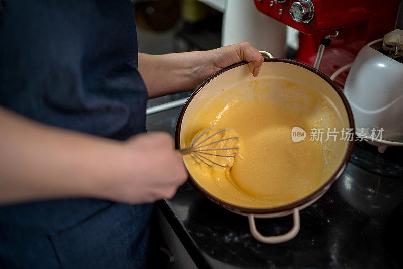 穿灰色围裙的年轻女子打破了鸡蛋