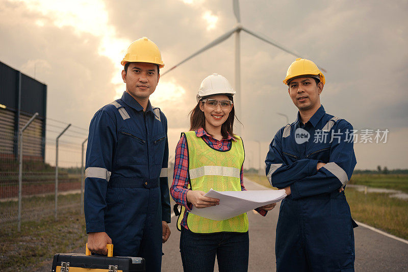 快乐三技术员工程师穿着制服站在风力发电机发电场检查风力发电机站。