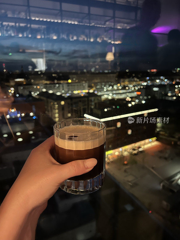 晚上在屋顶酒吧喝着浓咖啡马提尼，背景是城市的灯光
