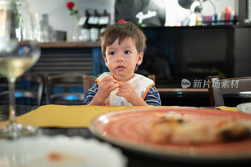 孩子在餐厅吃披萨在一个晚上的晚餐