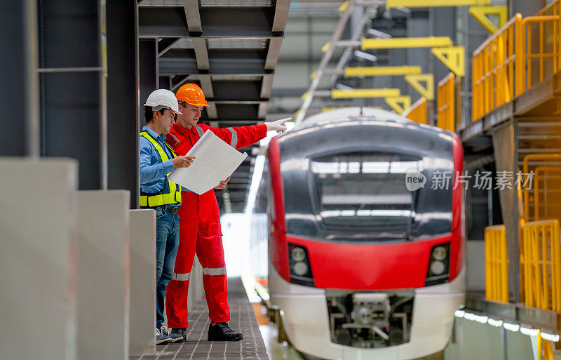 专业的工程师和技术人员在工厂车间的空轨列车或电气传动装置前与图纸或计划进行讨论。
