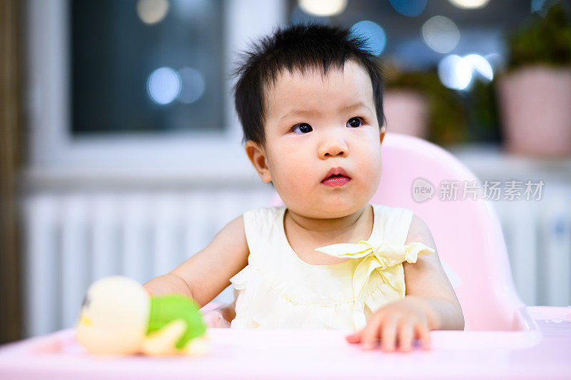 亚洲可爱的小婴儿坐在餐厅的婴儿餐椅上