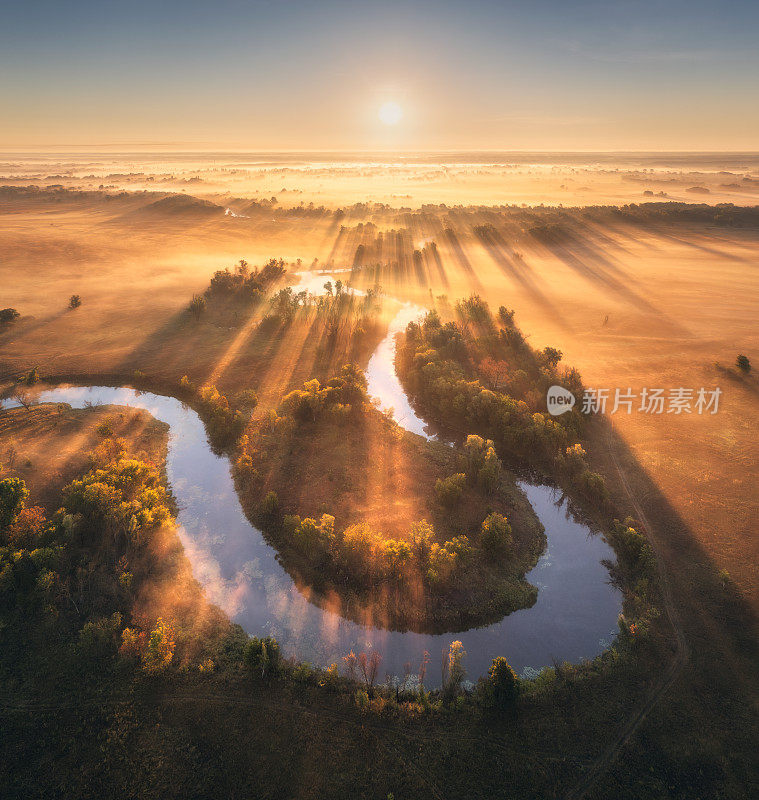 鸟瞰乌克兰秋天日出时低云中美丽弯曲的河流。河流、草地、田野、草地、橘树、秋天黎明金色的阳光。河岸的俯视图