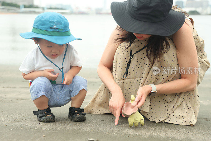 年轻的母亲和她的小儿子在海滩上玩耍