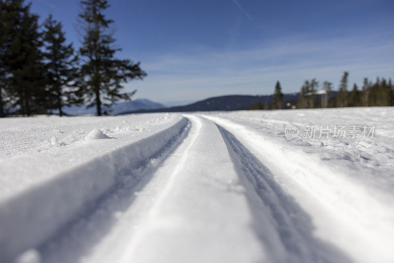 积雪覆盖的越野滑雪道与山在远处