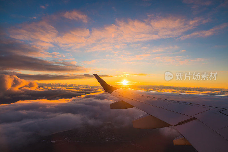 飞机在日落的天空中飞过海水和飞机的机翼。从飞机窗口看到的景象。在空中旅行。