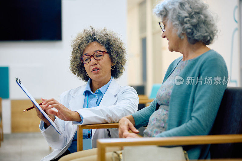女医生在候诊室和她的老病人一起检查医疗文件。