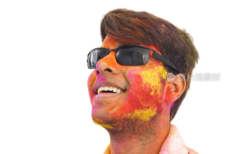 这是一幅美丽的大头照，一个快乐微笑的16岁印度小男孩戴着黑色时髦的太阳镜或护目镜，脸上露出笑容，露出牙齿，在透明的白色背景上，胡里粉漆的颜色很乱