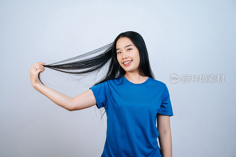 年轻的亚洲女子在白色背景下撩起她飘动的长直发