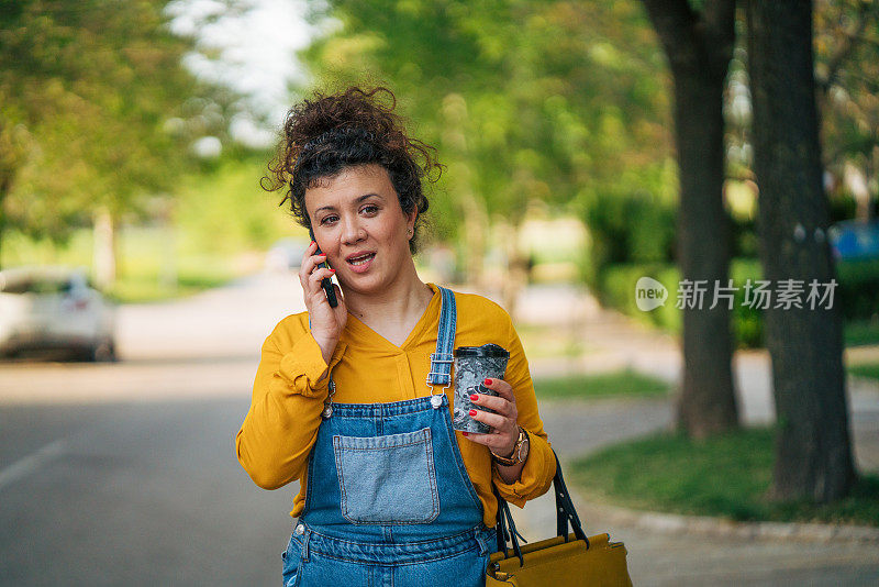 一个轻松的卷发女人一边走一边打电话。