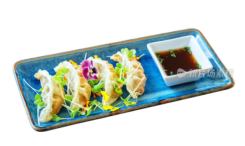 原汁原味的亚洲日本肉馅饺子，用陶瓷盘子和酱汁装饰鲜花。在白色的背景上。