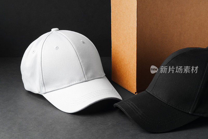 白色和黑色棒球帽在灰色表面对黑色背景