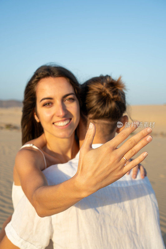 海滩求婚:快乐的女人展示订婚戒指