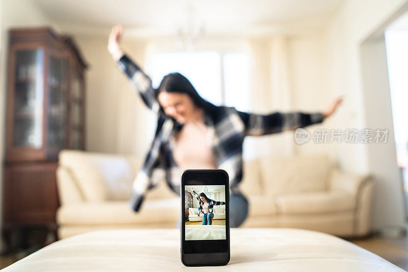 把注意力集中在手机屏幕上，背景中有一个女人在跳舞