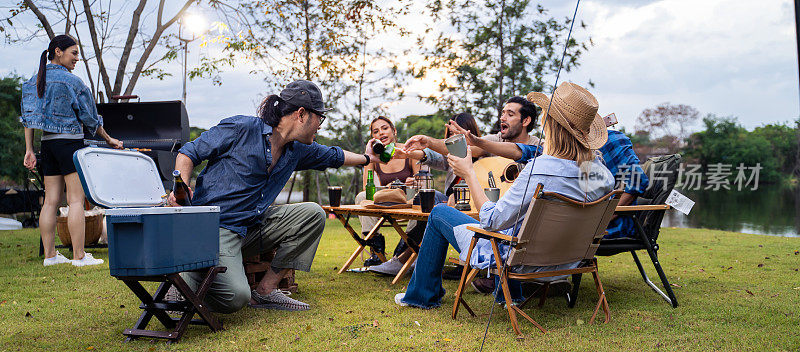 一群不同的朋友一起在帐篷里举行户外露营聚会。有魅力的年轻男女旅行者喝着酒精啤酒，享受在森林度假旅行中闲逛。