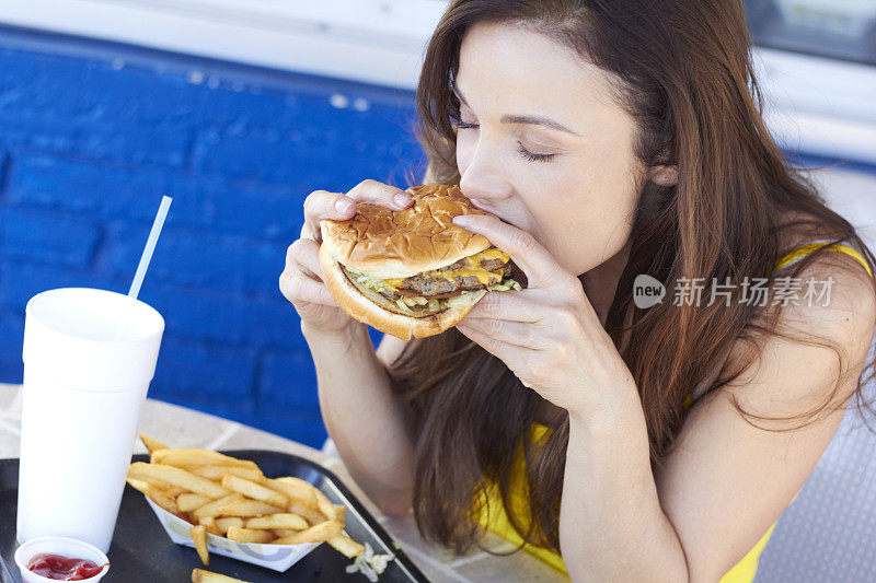 深色头发的女人正在吃快餐汉堡和薯条