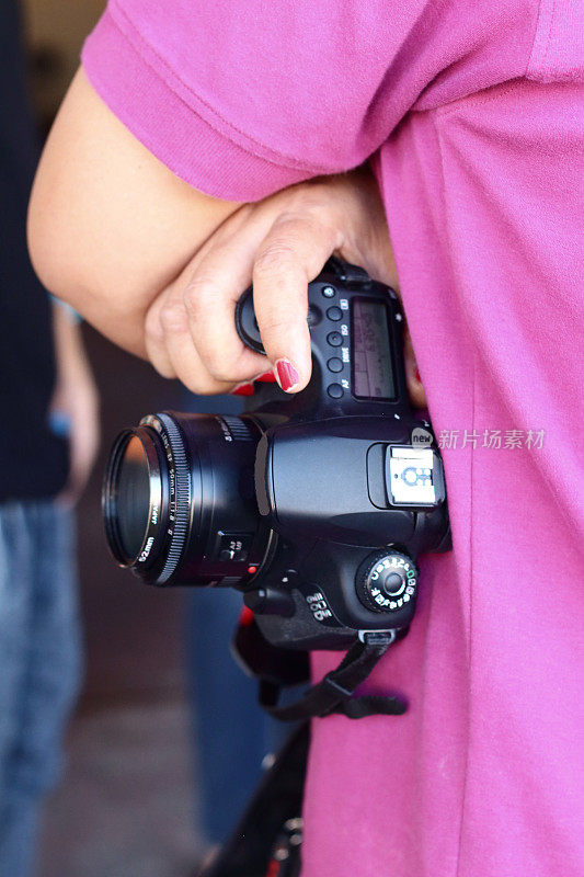 穿着粉红色衬衫拿着相机的摄影师。