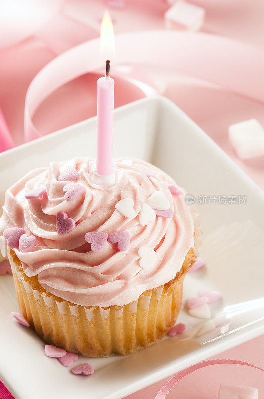女孩们的第一个生日蛋糕，上面有蜡烛、粉色糖霜和丝带