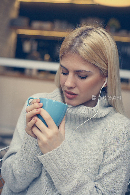 女学生一边听音乐一边喝咖啡。
