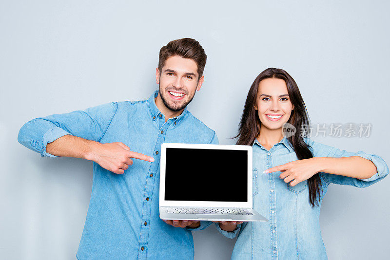 幸福的夫妇显示笔记本电脑和指向黑屏